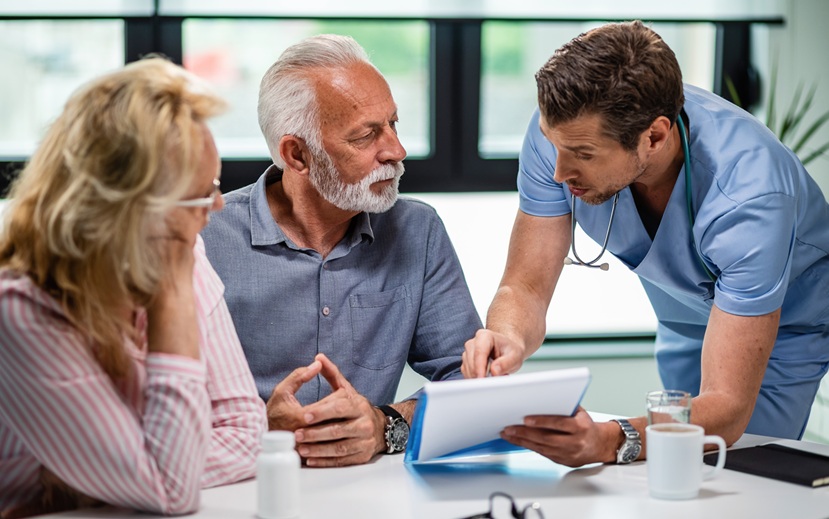 ernstige-arts-gesprek-met-senior-koppel-hun-medische-documenten-tijdens-afspraak-bij-kliniek-1.jpg