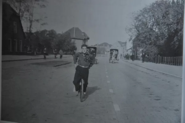 Poedel van Dam op zijn fiets terwijl hij een van zijn trucs uithaalt.